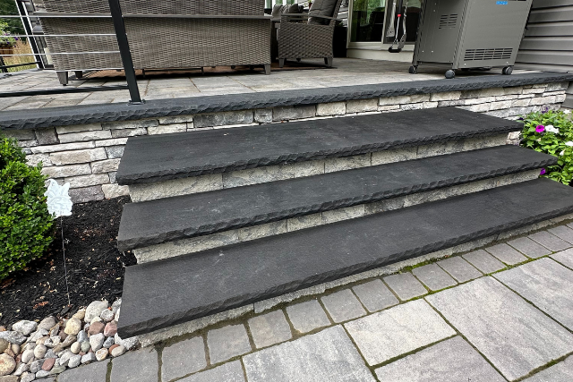 Black sandstone steps with patterned risers leading to an outdoor patio seating area