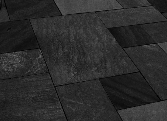 Black sandstone pattern cut natural stone installed as a patio with mixed-size rectangular slabs
