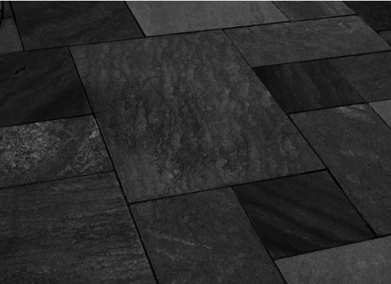 Black sandstone pattern cut natural stone installed as a patio with mixed-size rectangular slabs