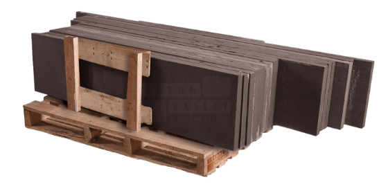 Black sandstone natural stone treads stacked on a wooden pallet for outdoor staircases