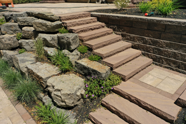Brownstone natural stone staircase with boulders and retaining wall in a garden landscape