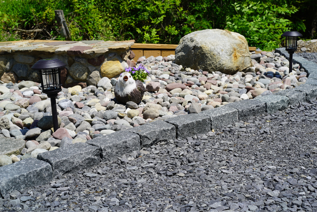 Mixed river rock garden bed with granite cobble border and solar lighting accents