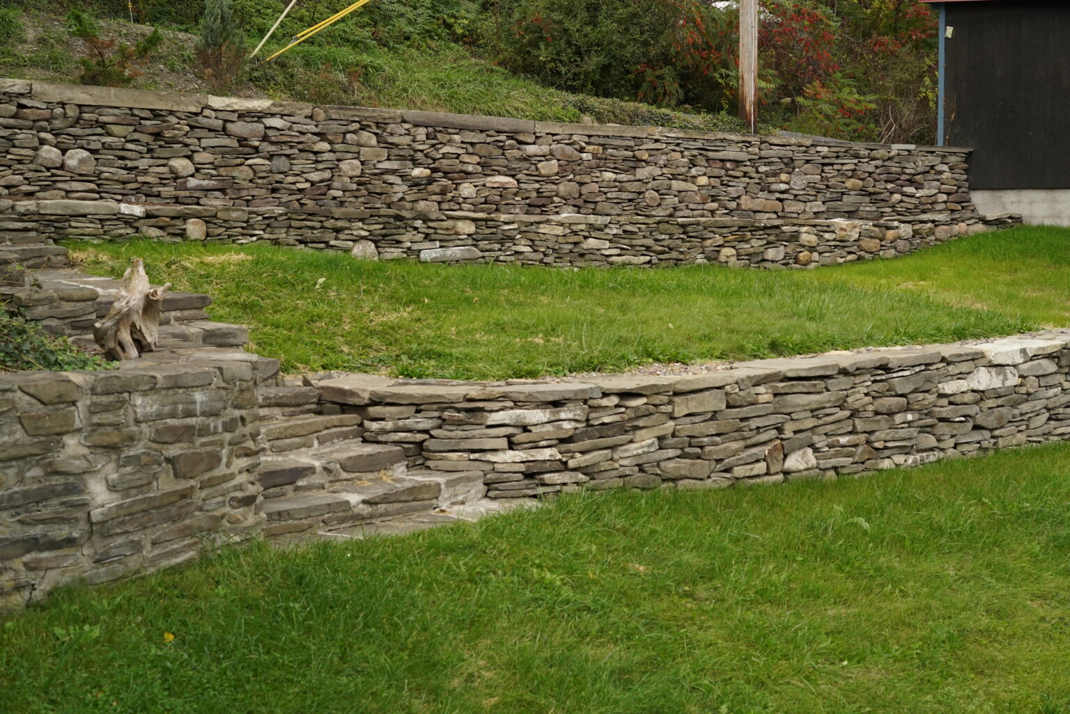 Natural stone wallstone retaining walls on a landscaped lawn with tiered garden design