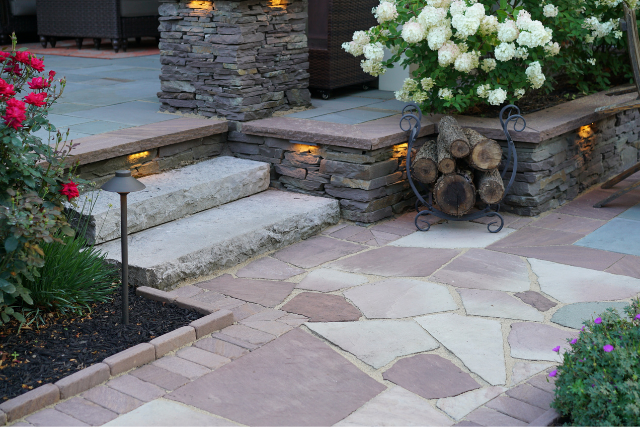 Multi-color flagstone patio with stone steps, accent lighting, and hydrangea plantings at a residential entry
