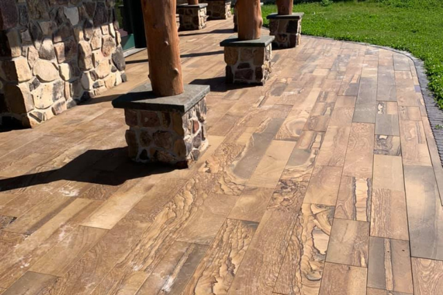 Warm brown sandstone pattern cut patio with rustic stone pillars and timber posts
