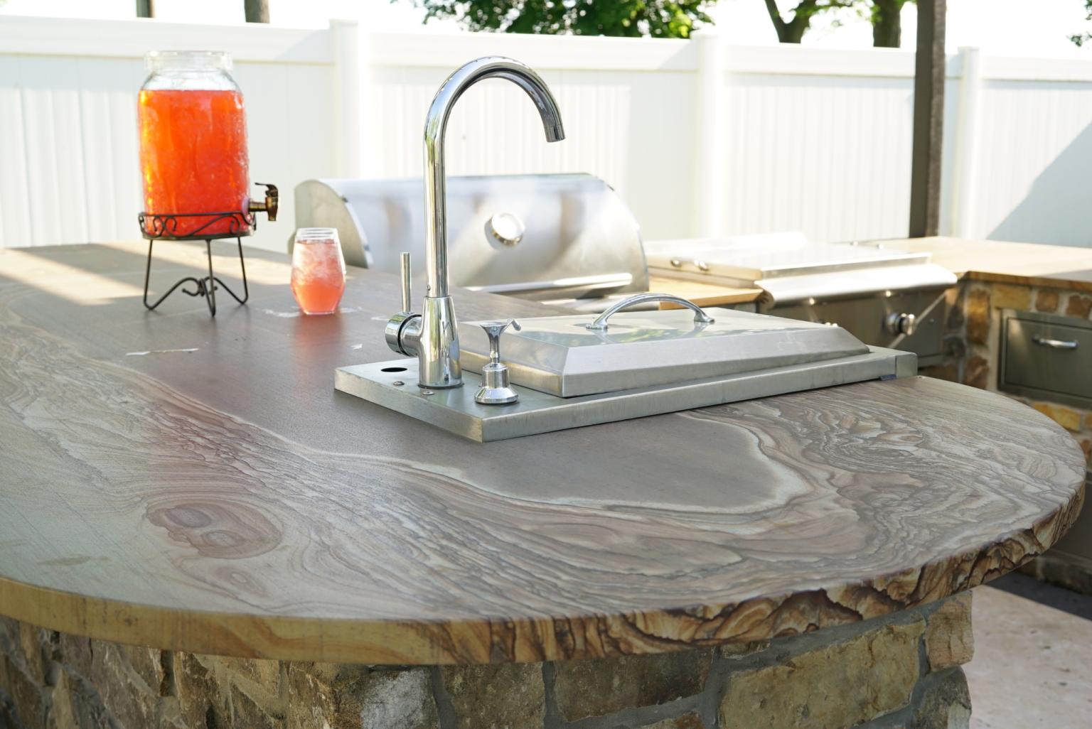 Natural stone slab countertop with wood-grain veining on an outdoor kitchen with sink and grill