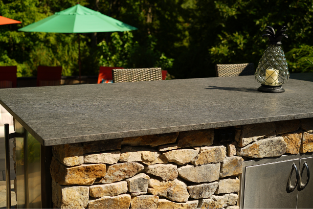 Natural stone slab countertop on a stone veneer outdoor kitchen bar