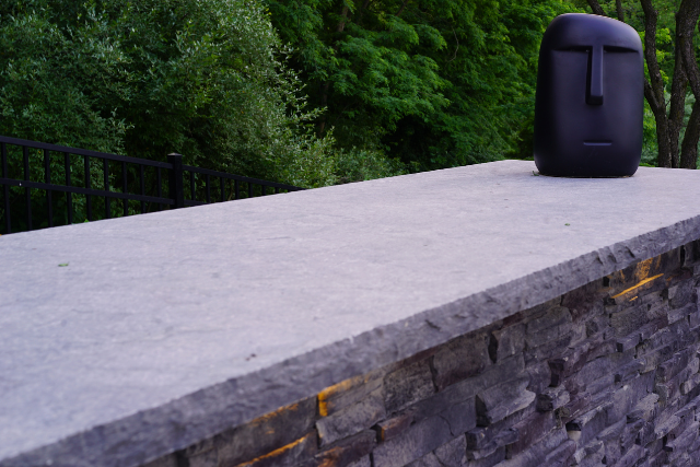 Natural stone slab wall cap on a stacked stone wall with garden view