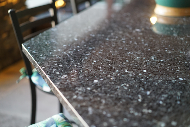 Natural stone slab dining table with speckled surface and chairs in an indoor setting