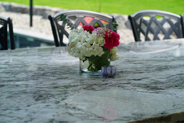 Natural stone slab outdoor dining table with flowers and chairs in a backyard