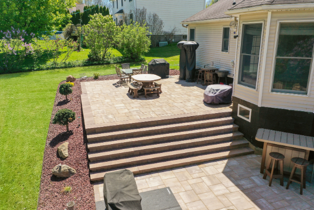Natural stone treads leading to a paver patio with outdoor dining in a backyard