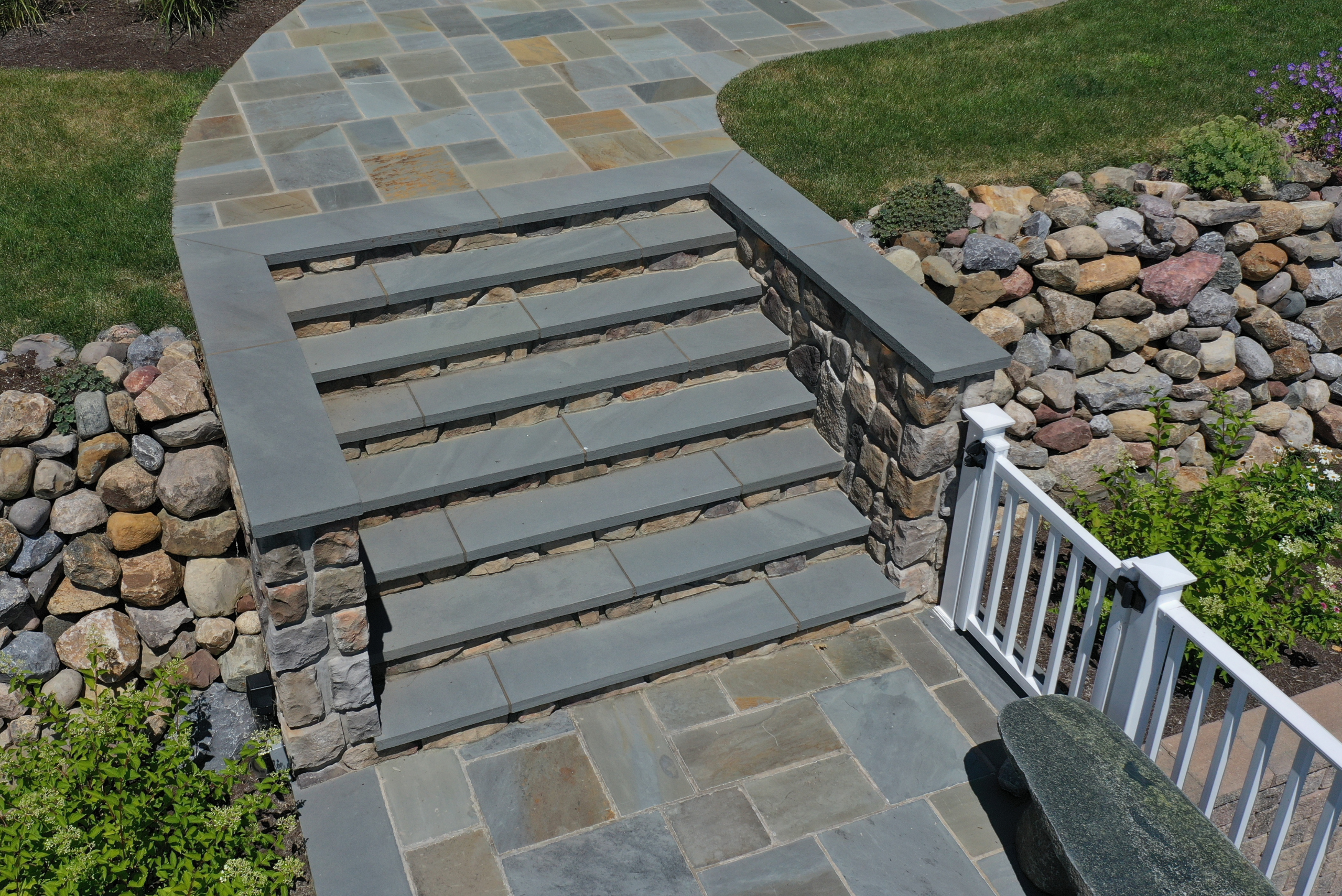 Bluestone natural stone treads on an outdoor staircase leading to a flagstone patio walkway