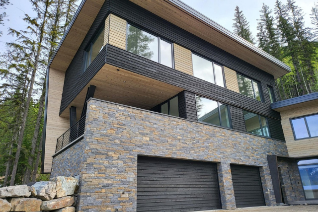 Natural stone veneer cladding on a modern home exterior with wood and metal siding