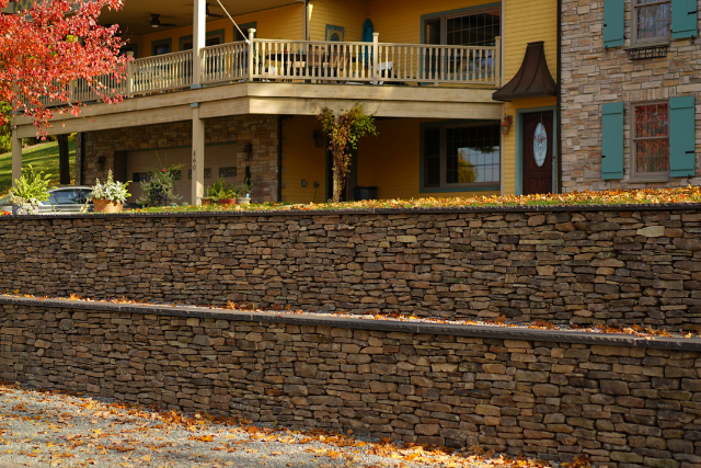 Natural stone wallstone retaining wall in front of a two-story home with balcony