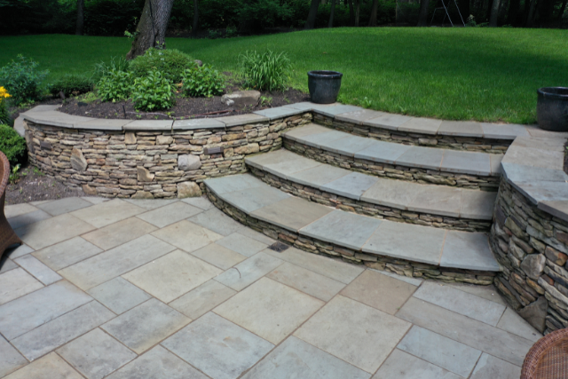 Curved natural stone wallstone steps with stone seating wall and paver patio