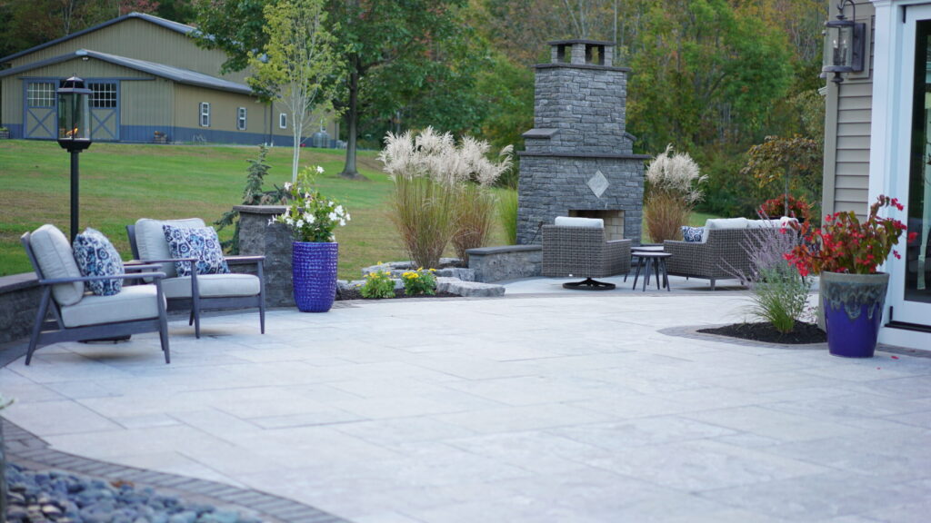 Natural stone patio with outdoor fireplace and seating wall in a backyard landscaping project